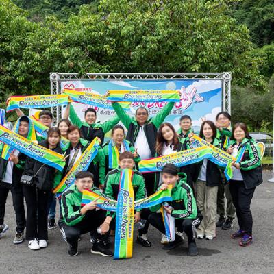 戶外運動會路跑活動，公司同仁拿出客製化運動毛巾在迎賓拍照區前面一起大合照